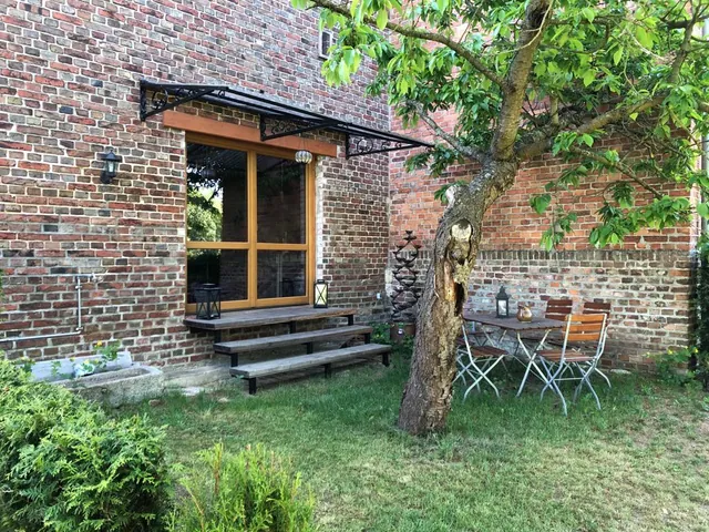 Überdachter Eingang der Erdgeschosswohnung mit Bistrotisch im Garten